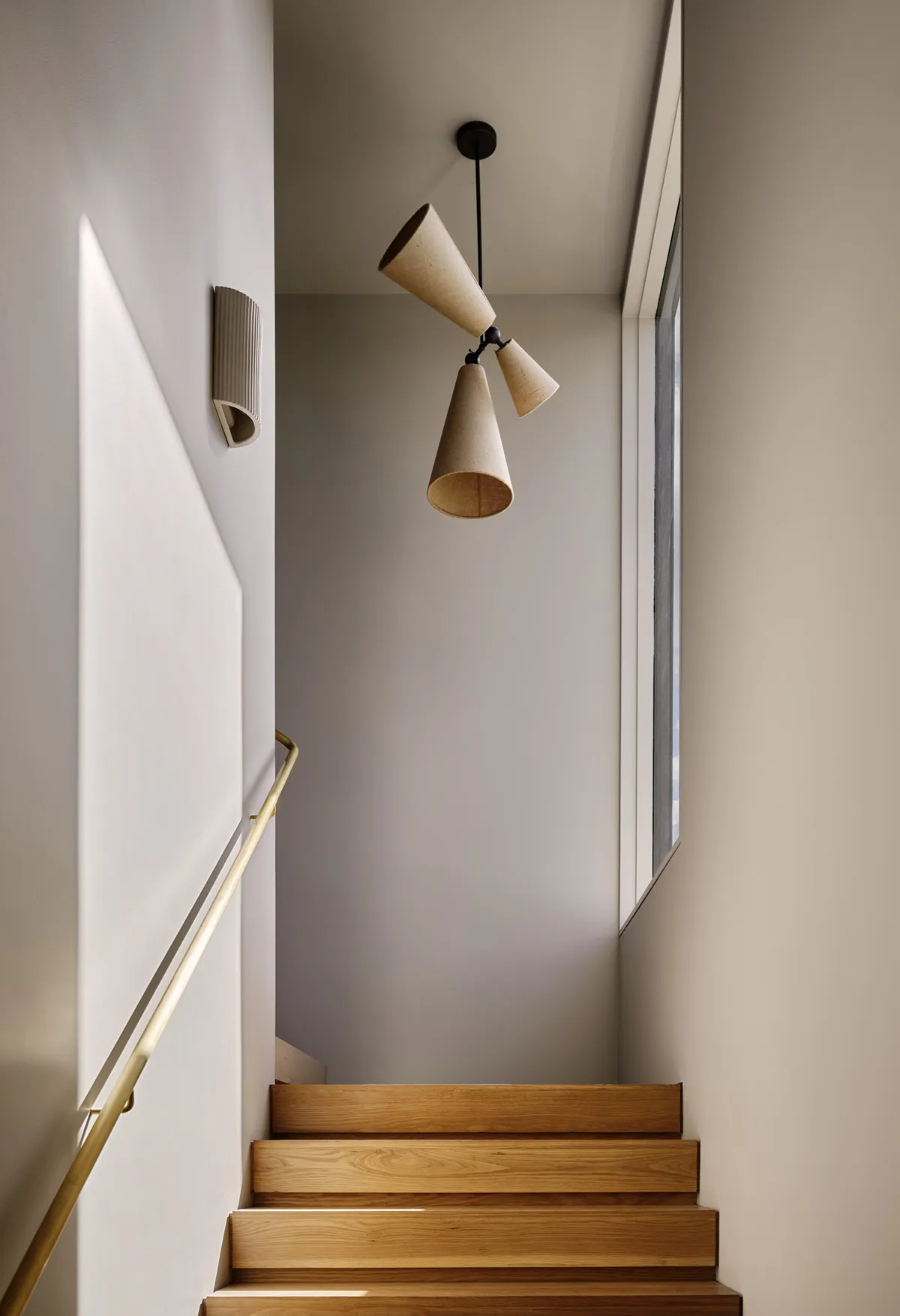 Modern interior with wooden stairs and brass handrail, focusing on the architectural and design elements.