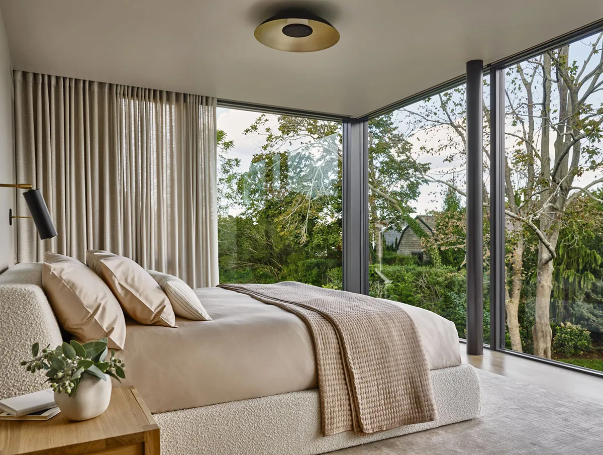 Contemporary bedroom featuring textured furniture and large windows overlooking greenery.