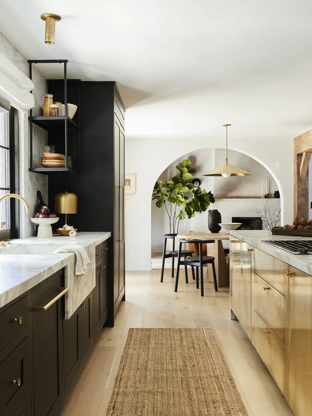 A modern kitchen featuring black and gold cabinets, marble countertops, and brass accents.