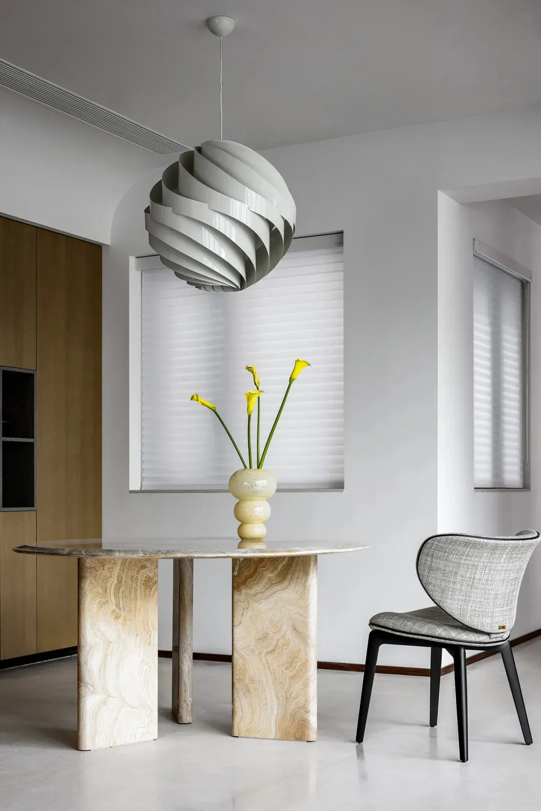 A modern dining room with a marble table and a unique pendant light hanging above it.