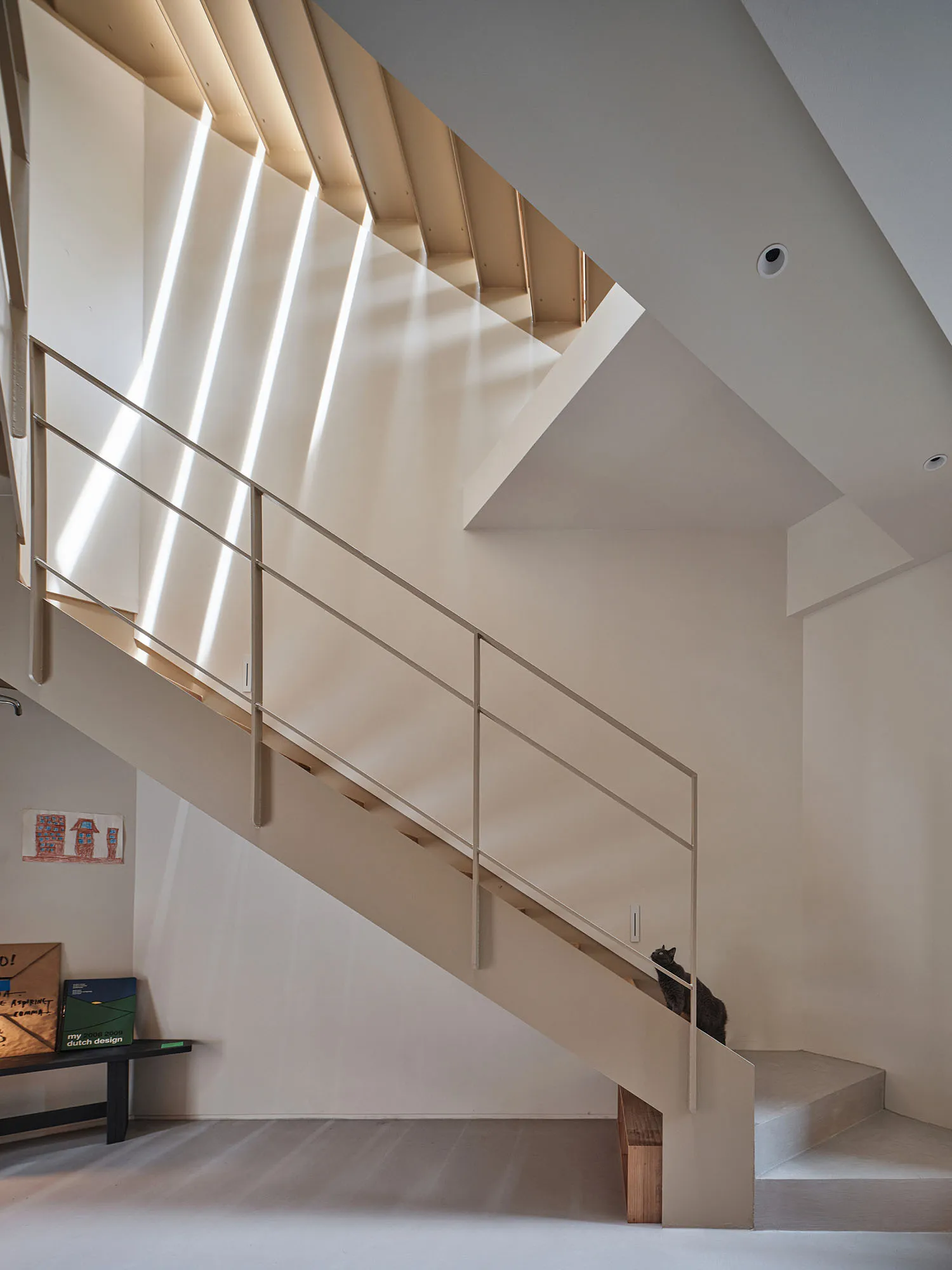 Modern, industrial-style staircase with metallic railing and steps, featuring geometric shapes and a minimalist aesthetic.