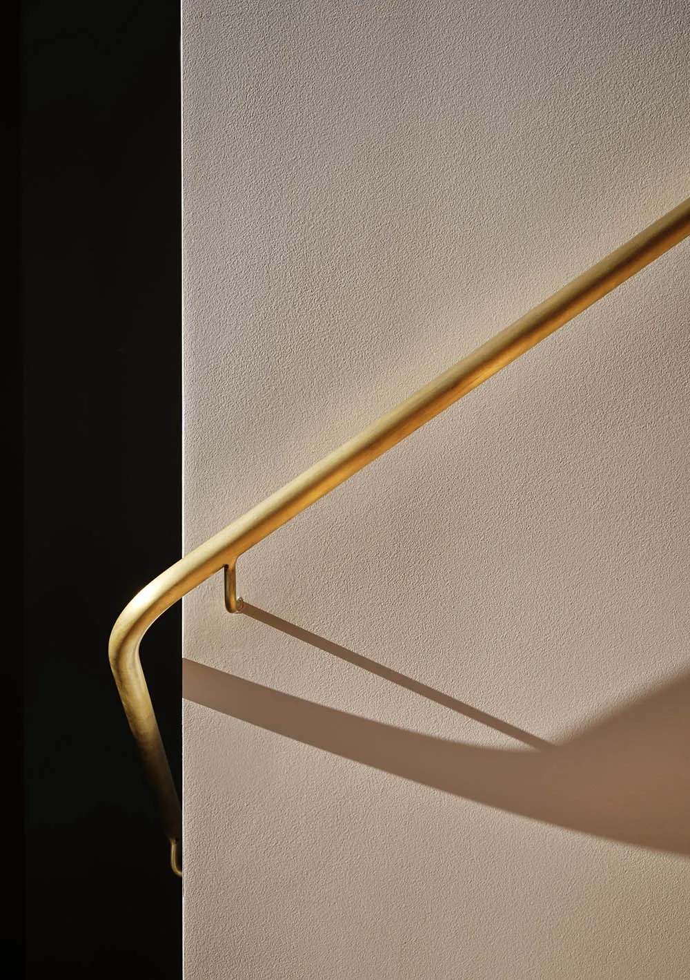 A metallic handrail with a lighting shadow in an interior design setting.