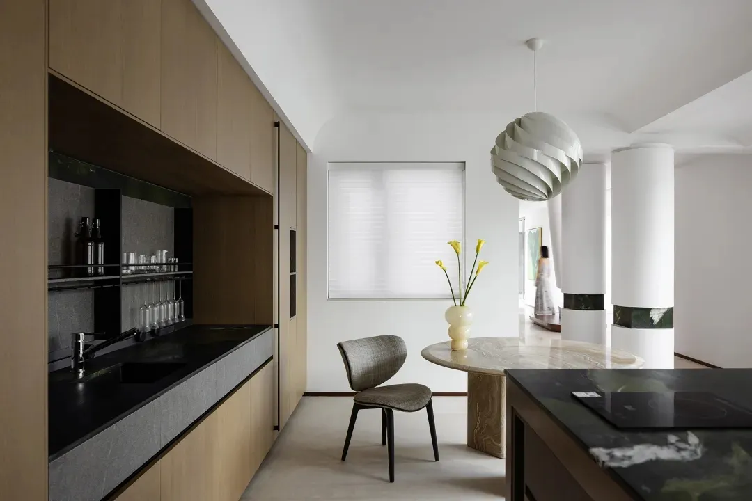 Minimalist residential kitchen with marble countertops and pendant light.