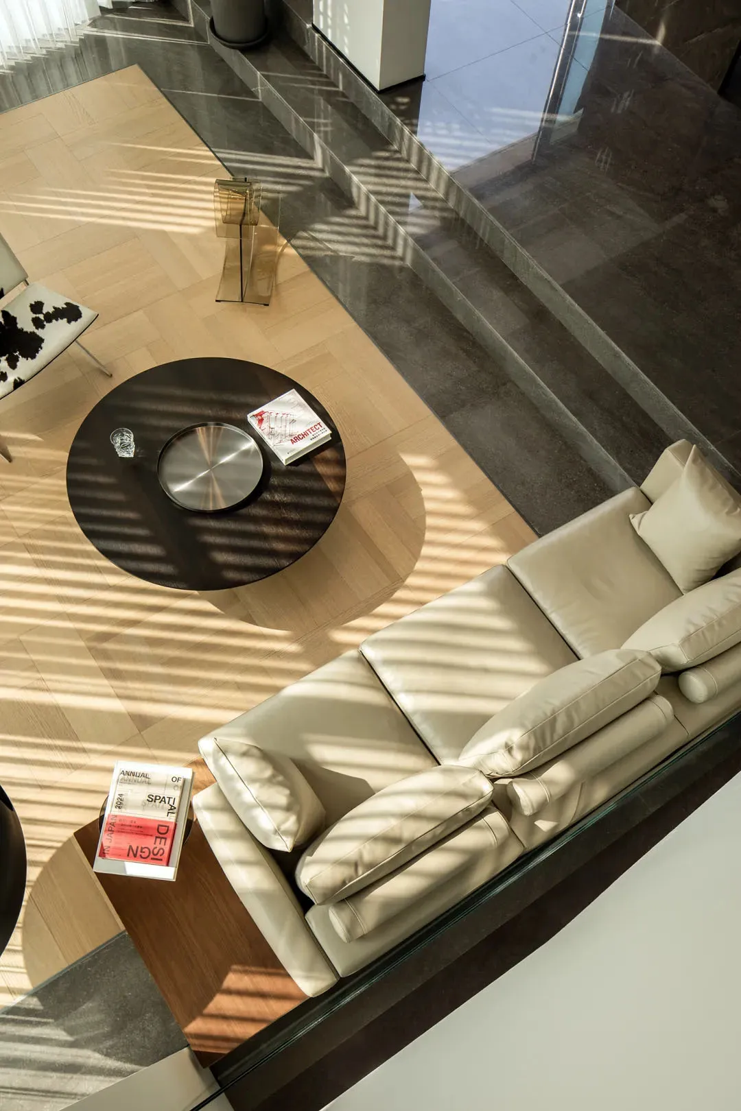 Modern living room featuring hardwood flooring, a beige sofa, and a round black coffee table.