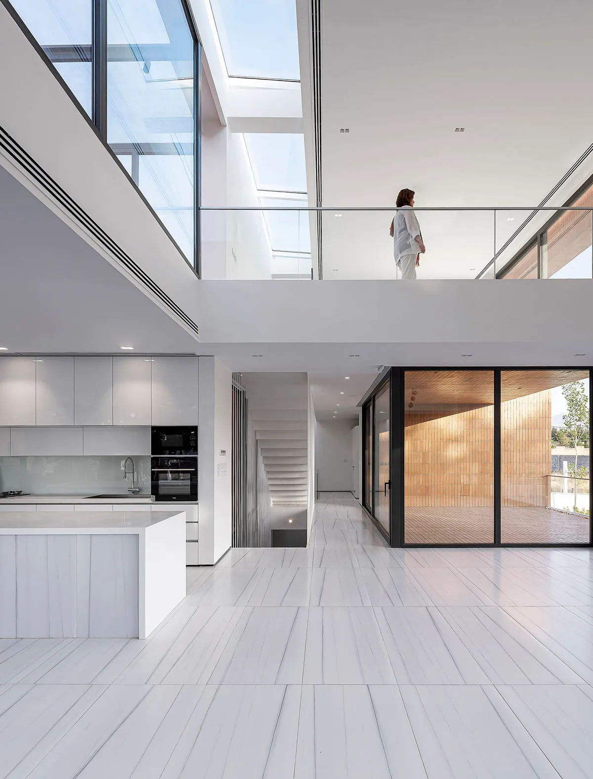 A modern residential kitchen featuring white tiles and glass walls