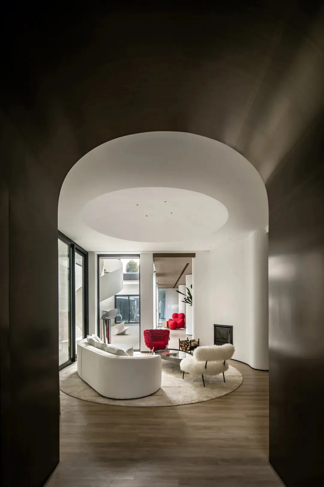 Modern living room with white marble floor, red accent chair, and white sofa.