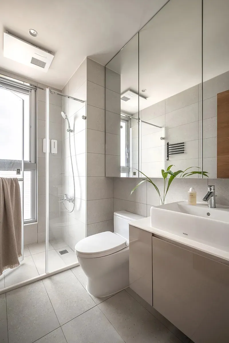 Modern minimalist bathroom featuring grey tiled walls and floor, a glass shower enclosure, and a floating vanity with a white