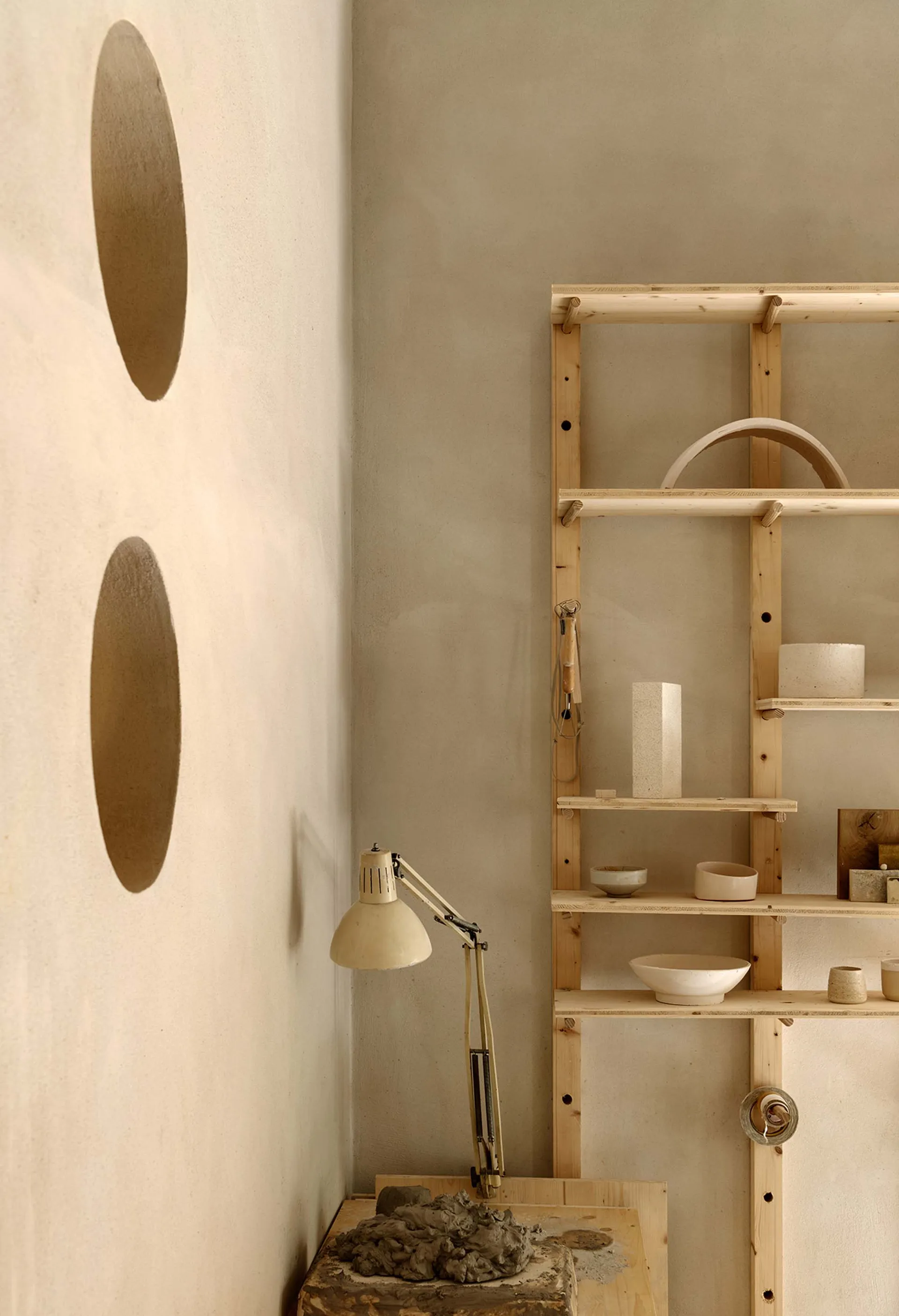 Minimalist ceramic workshop with wooden shelves and clay tools.