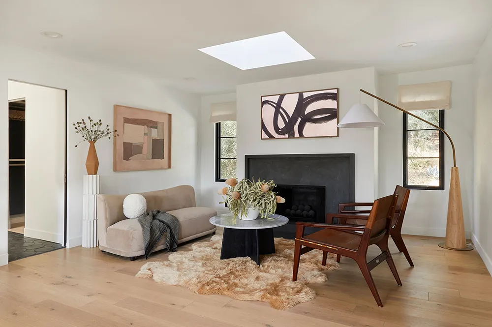 Minimalist living room with hardwood flooring, geometric art, and a fireplace.
