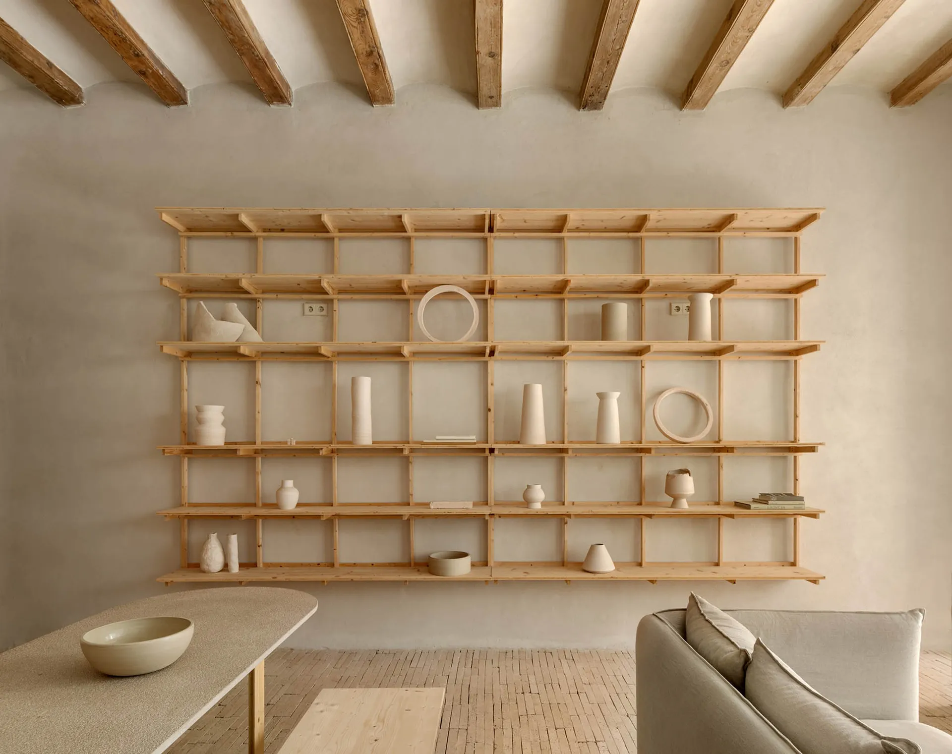 A minimalist shelf display featuring various wooden objects in a serene, neutral-toned room.