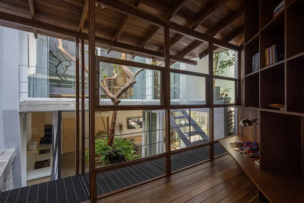 Modern residential interior featuring exposed wooden beams, large windows, and concrete flooring.