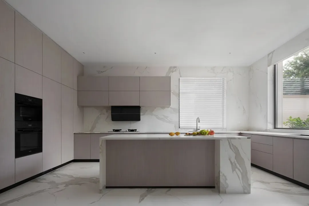 Modern kitchen with marble countertops and island, featuring sleek cabinetry and a clean, minimalist aesthetic.