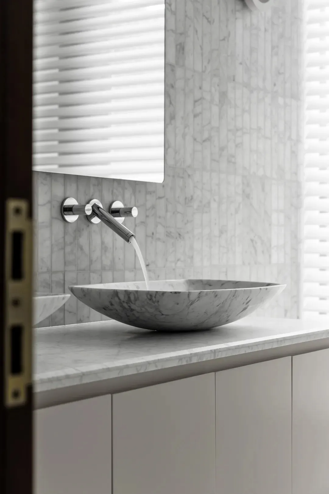A minimalist bathroom with a marble countertop featuring a sleek, modern sink and faucet.