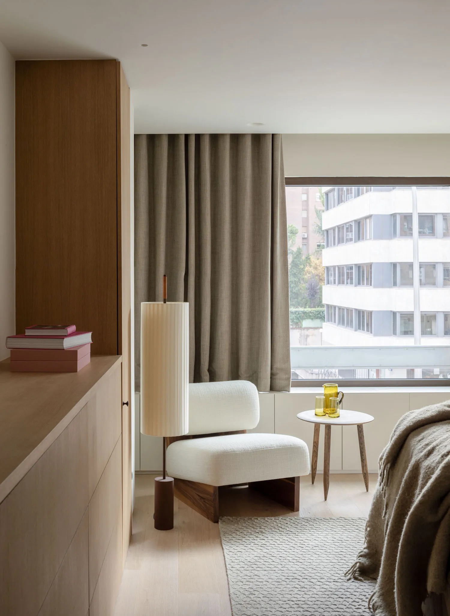 Modern minimalist bedroom featuring sleek white furniture, wooden accents, and floor-to-ceiling windows draped with sheer fab