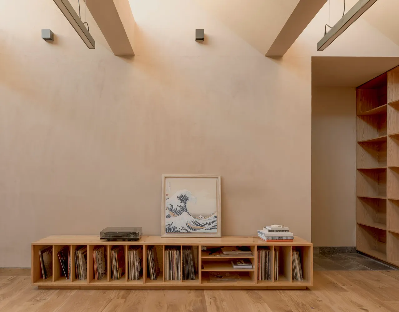 A minimalist living room featuring wooden shelves and a wooden floor.