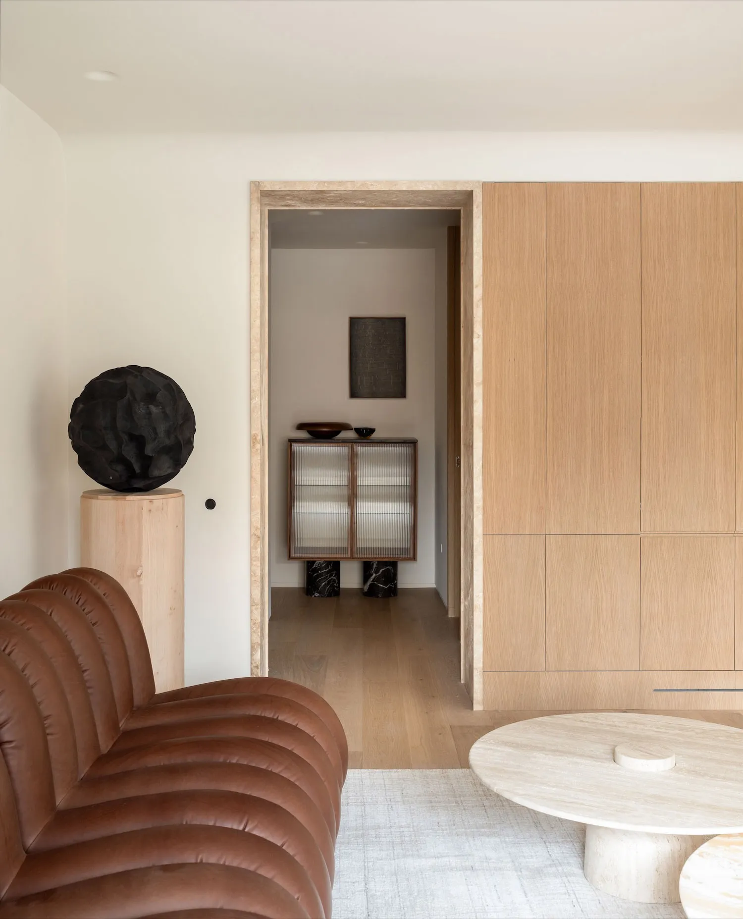 A modern living room featuring wooden cabinets, a brown leather couch, and a stone coffee table.