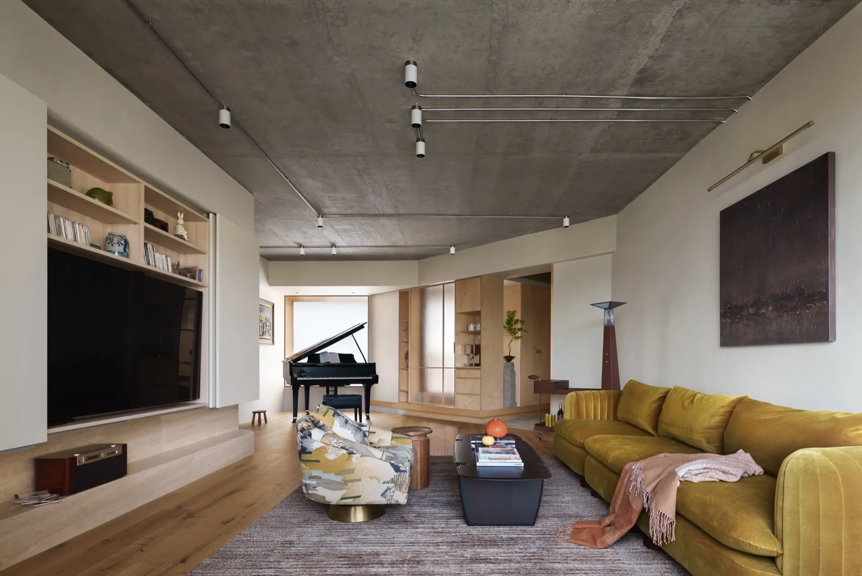 A modern living room with concrete floors, a yellow sofa, and a grand piano.