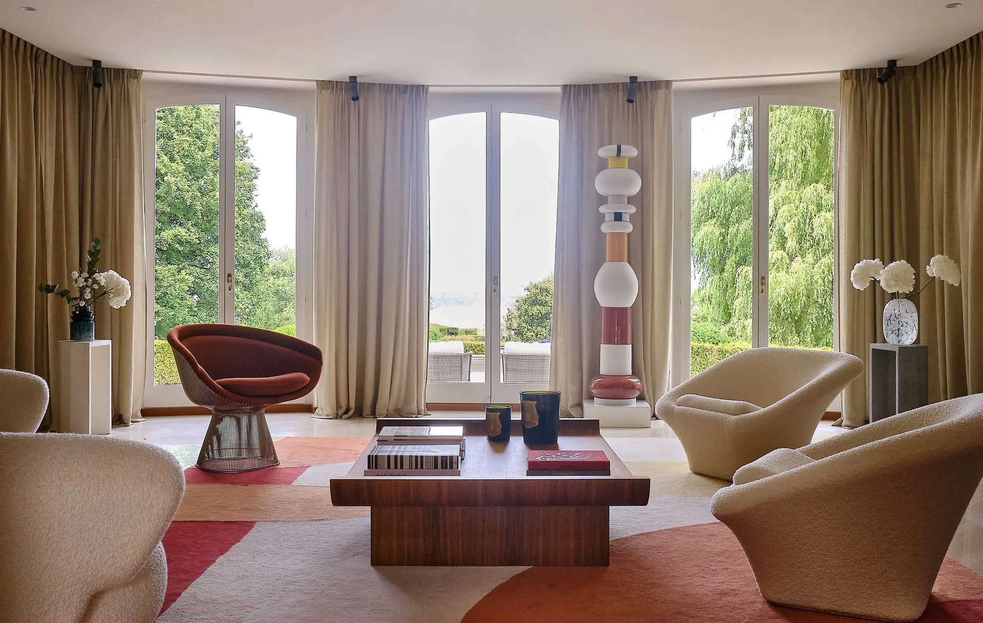 A modern living room featuring a wooden coffee table, plush armchairs, and decorative elements in a contemporary design setti
