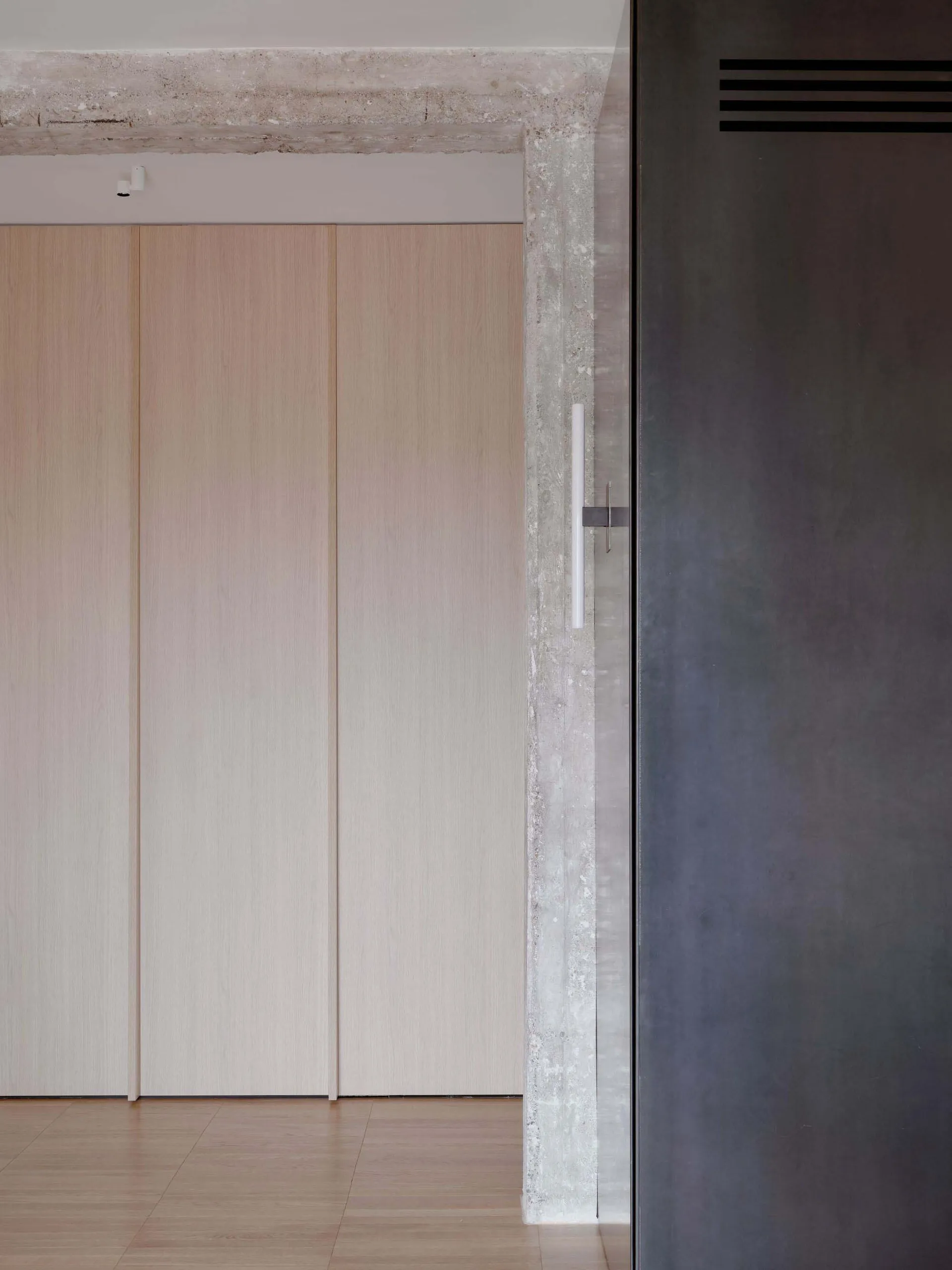 Modern minimalist interior with wooden closet doors and a concrete edge, featuring a sleek, minimalist design.