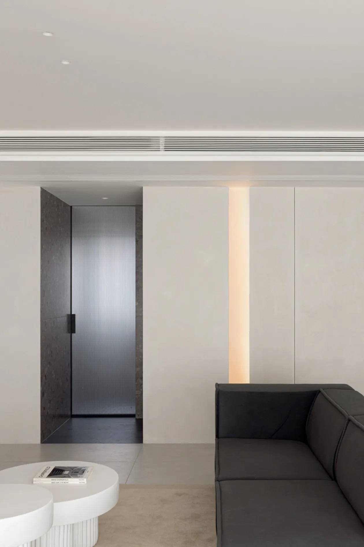 A modern minimalist living space featuring minimalist furniture and a concrete floor.