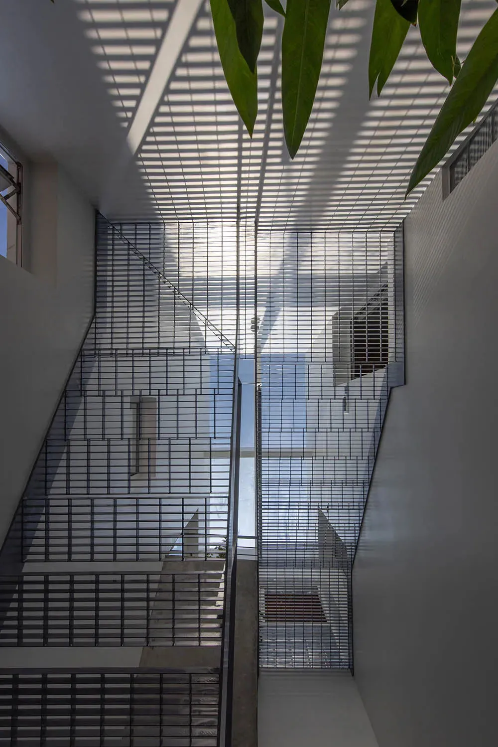 Modern staircase featuring a metal grid ceiling design, providing unique lighting and structural aesthetic.