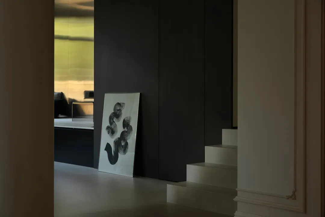 A modern living room with a metallic clad wall and abstract artwork in a minimalist style.