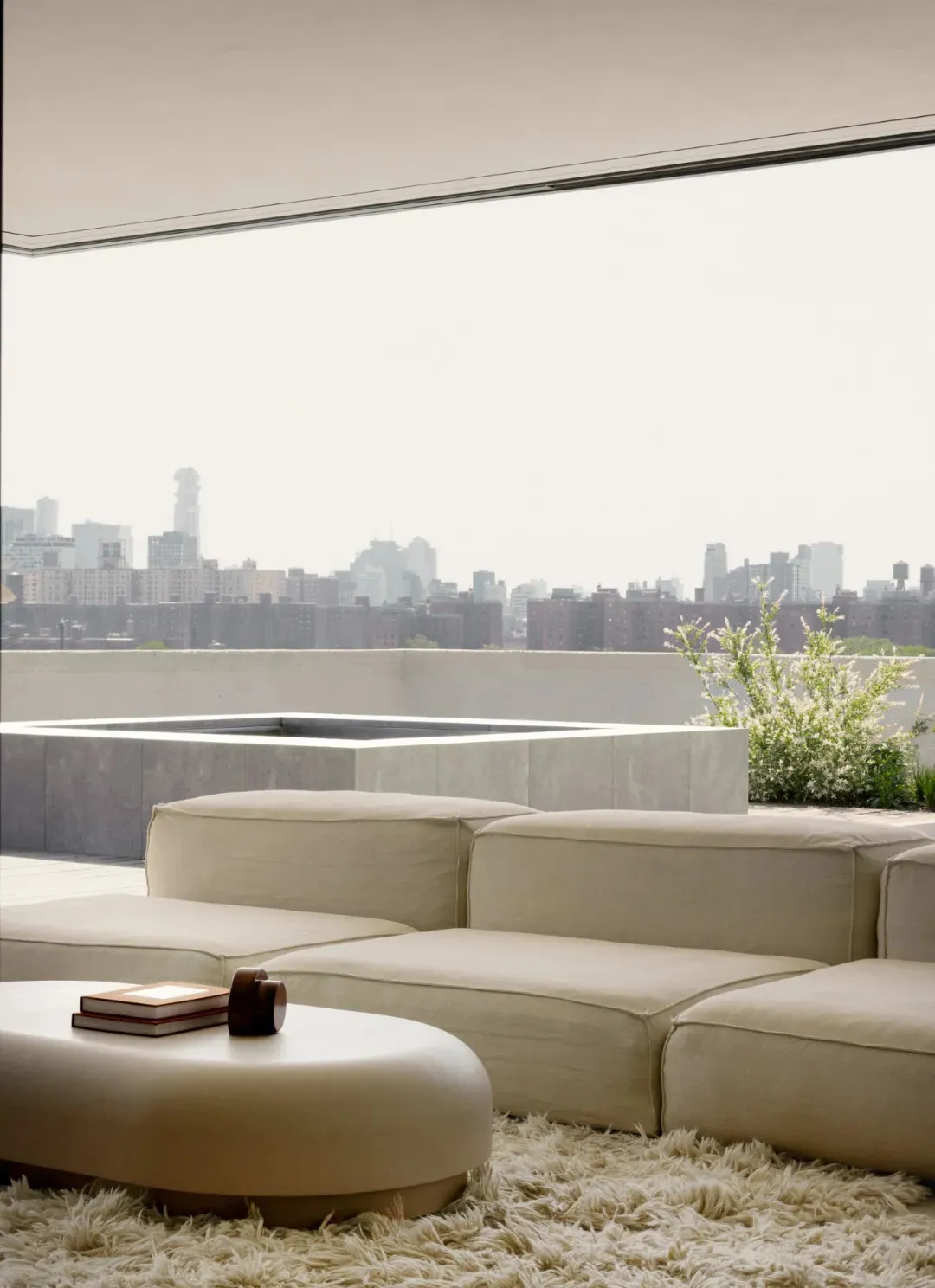 Modern, minimalist living room with beige upholstered furniture and a circular coffee table on a white rug.