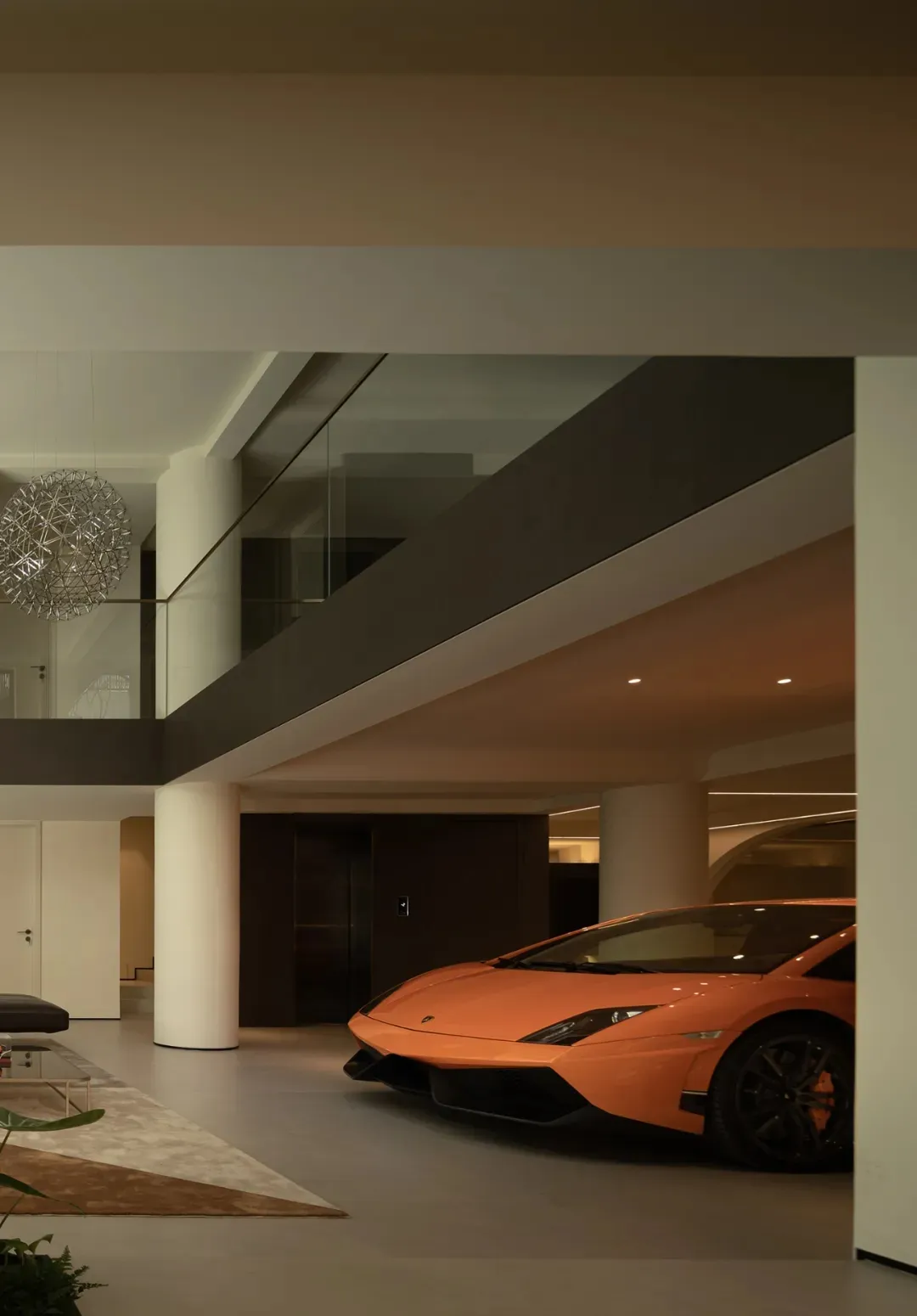 A modern, minimalist space featuring exposed concrete walls and a sleek, orange sports car parked inside.