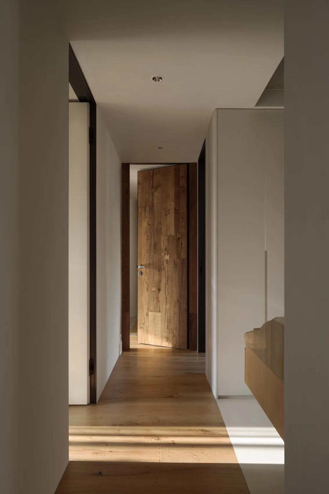 A wooden corridor with a minimalist design, featuring clean lines and warm, natural wood flooring.