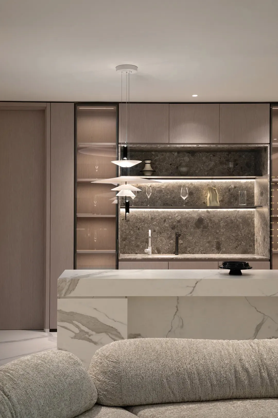 Modern kitchen interior with marble countertops, glass shelves, and minimalist design.