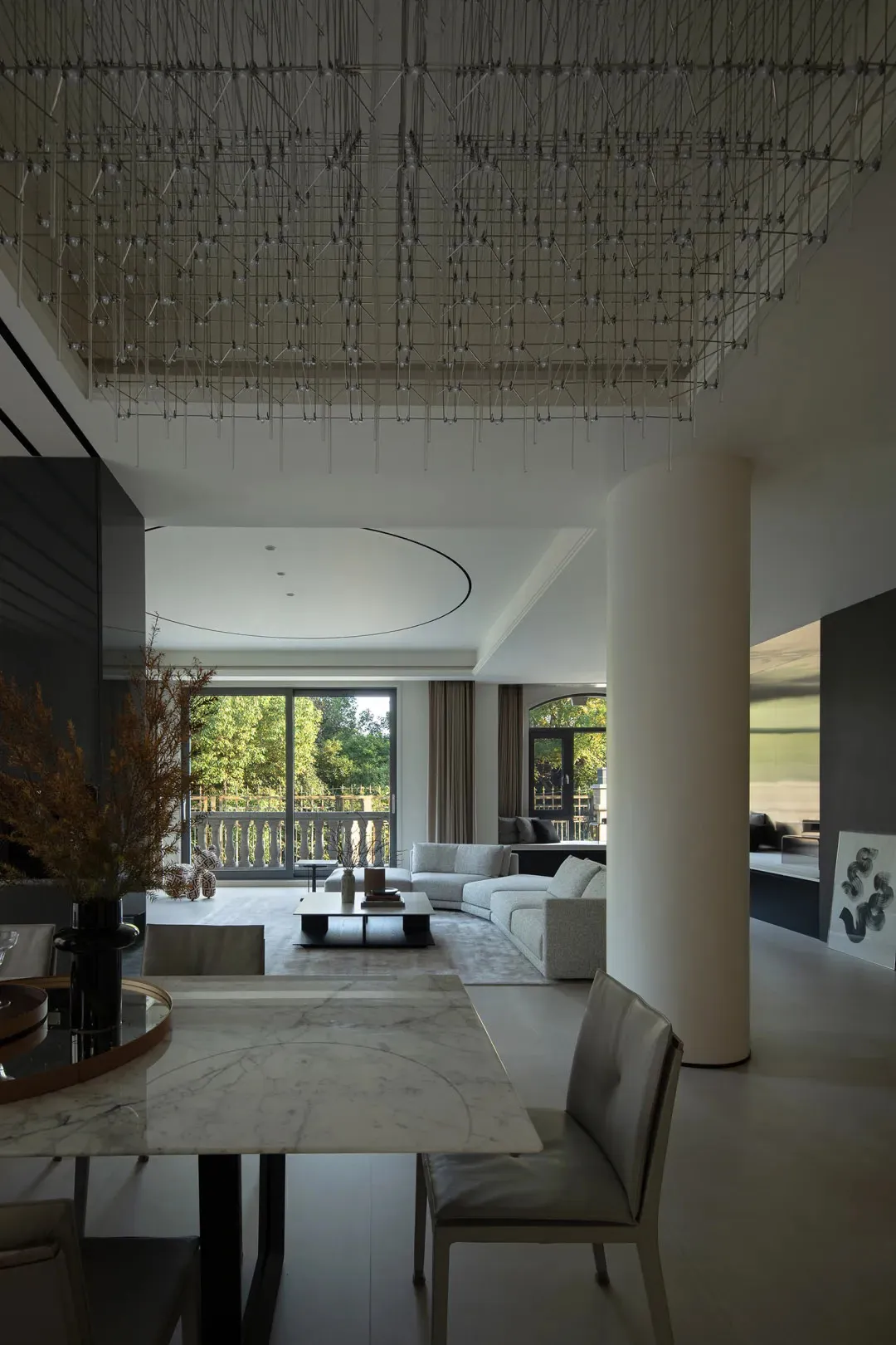 Minimalist modern living room with white marble table, glass chandelier, and leather furniture, featuring large windows and o