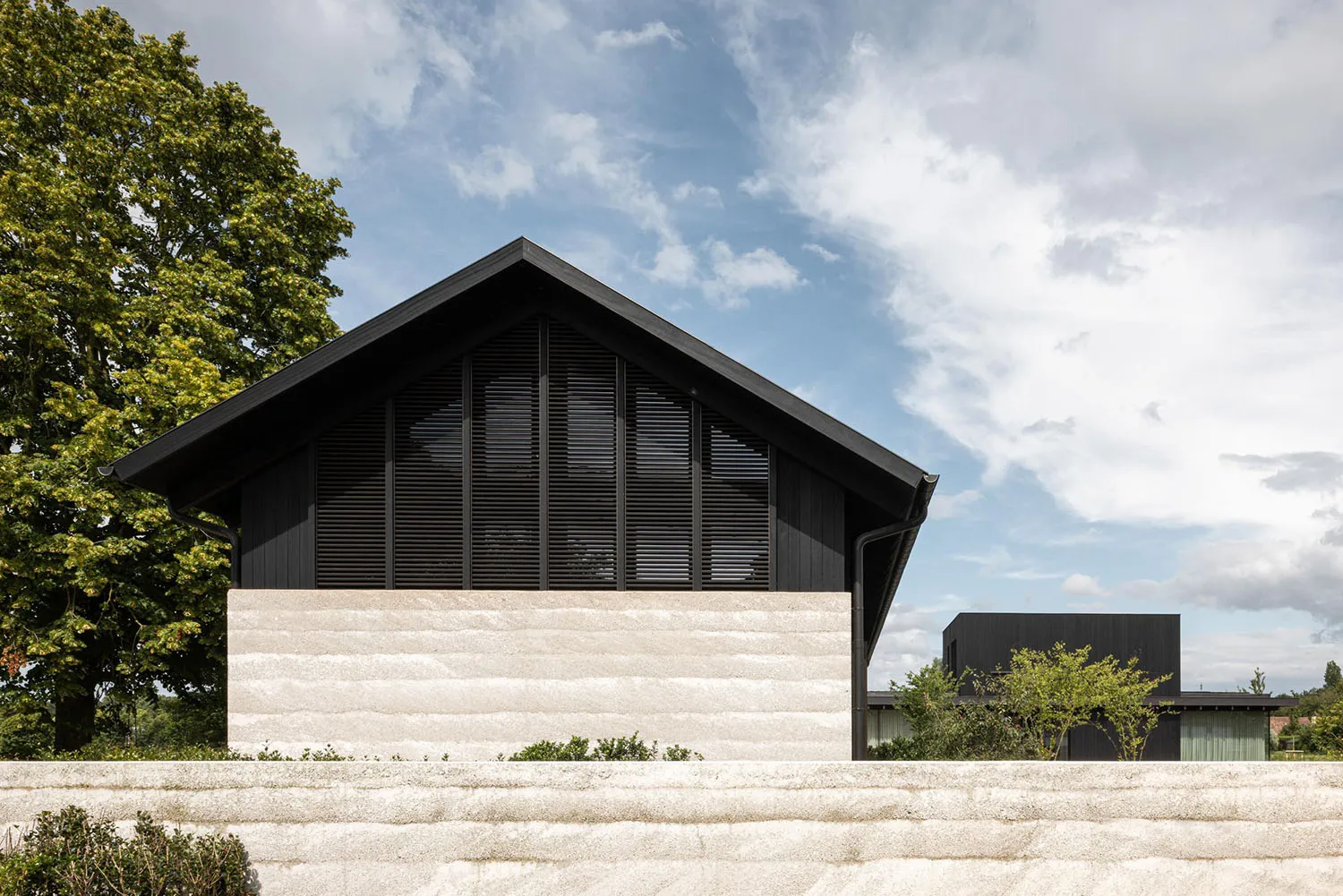 Modern house exterior with concrete base and black wooden slats on the upper structure.