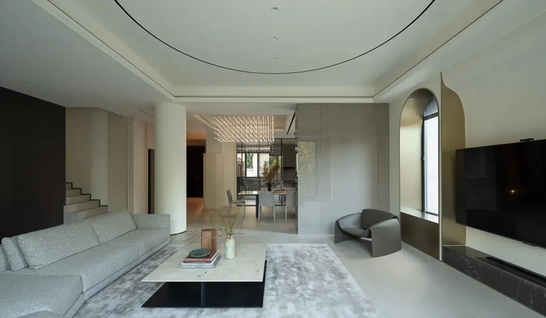 A modern living room with a minimalist design, featuring concrete walls, a white marble coffee table, and a ceiling light fix