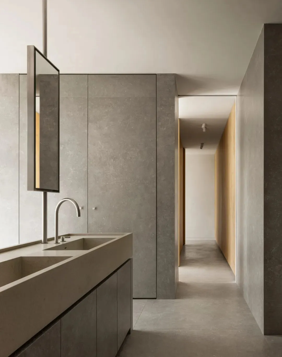 Modern minimalist bathroom featuring concrete tile flooring and walls, with a sleek faucet and minimalist design elements.