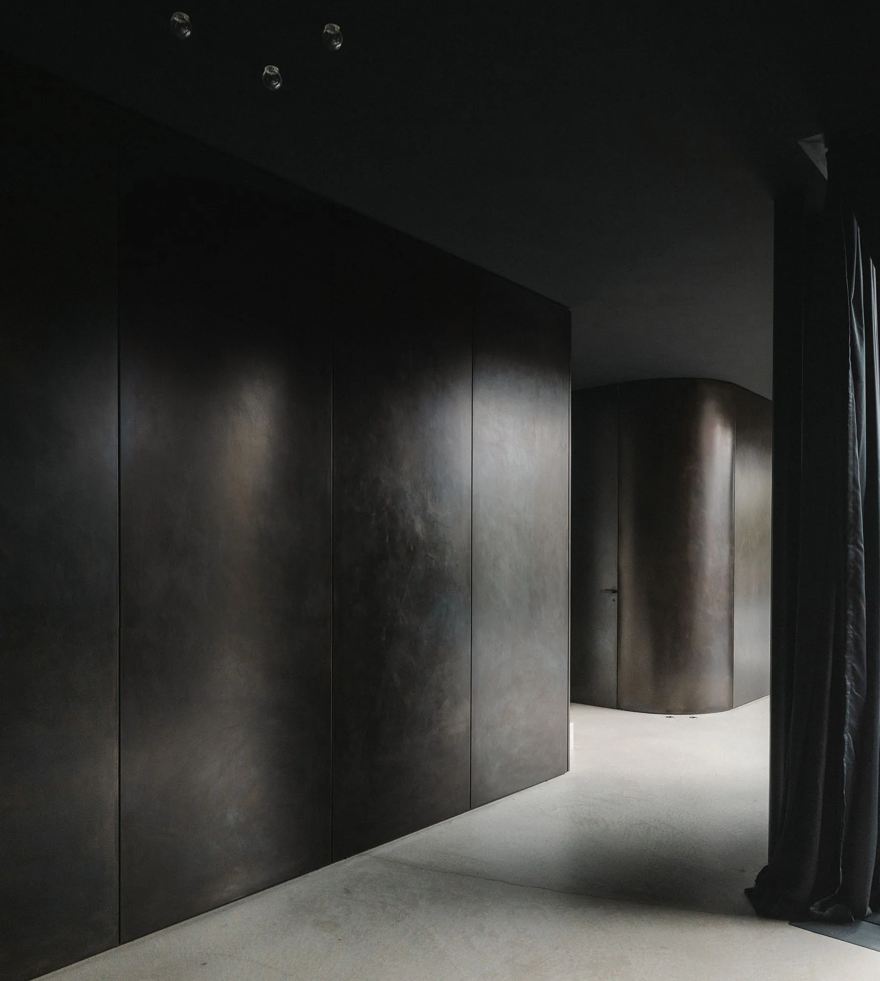 Modern minimalist interior with metallic walls and floor, featuring clean lines and geometric shapes.