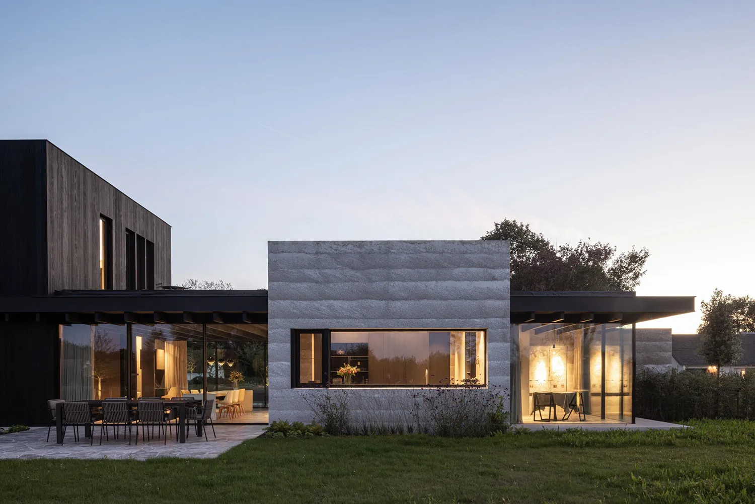 Modern residential exterior featuring stone and concrete materials at dusk.