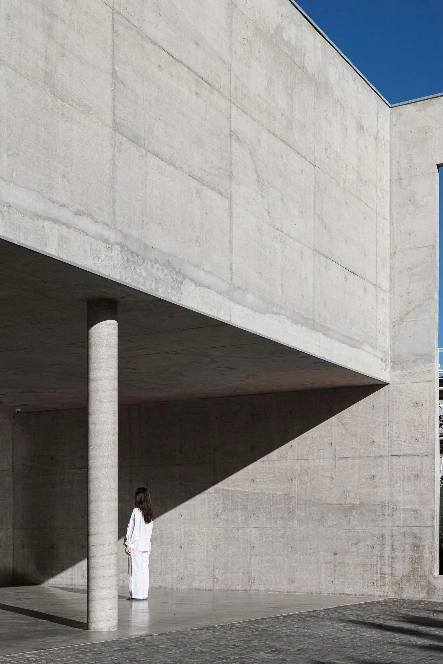 A modern architecture building made of concrete with a person standing in front.