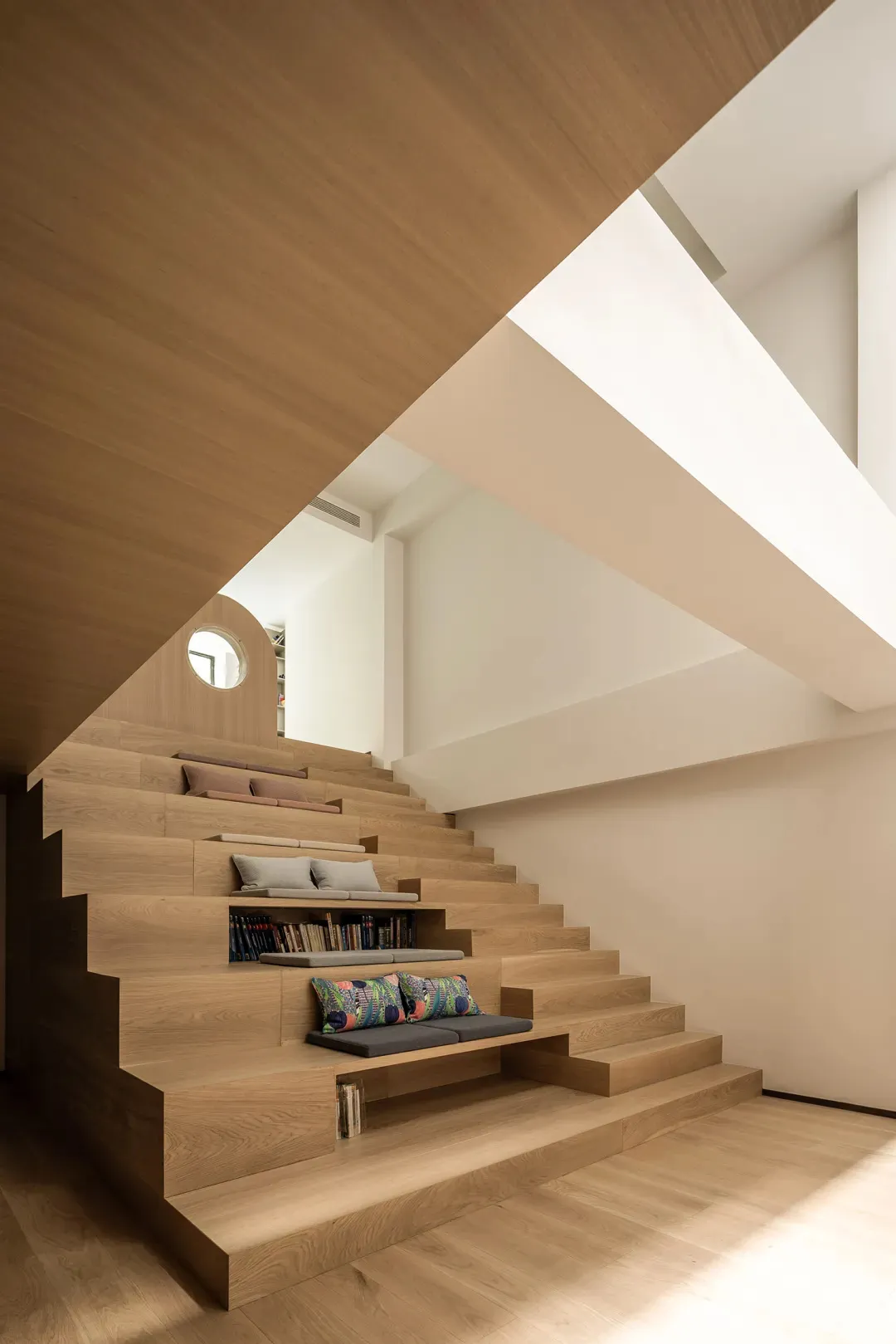 Modern wooden staircase featuring built-in seating and shelving.
