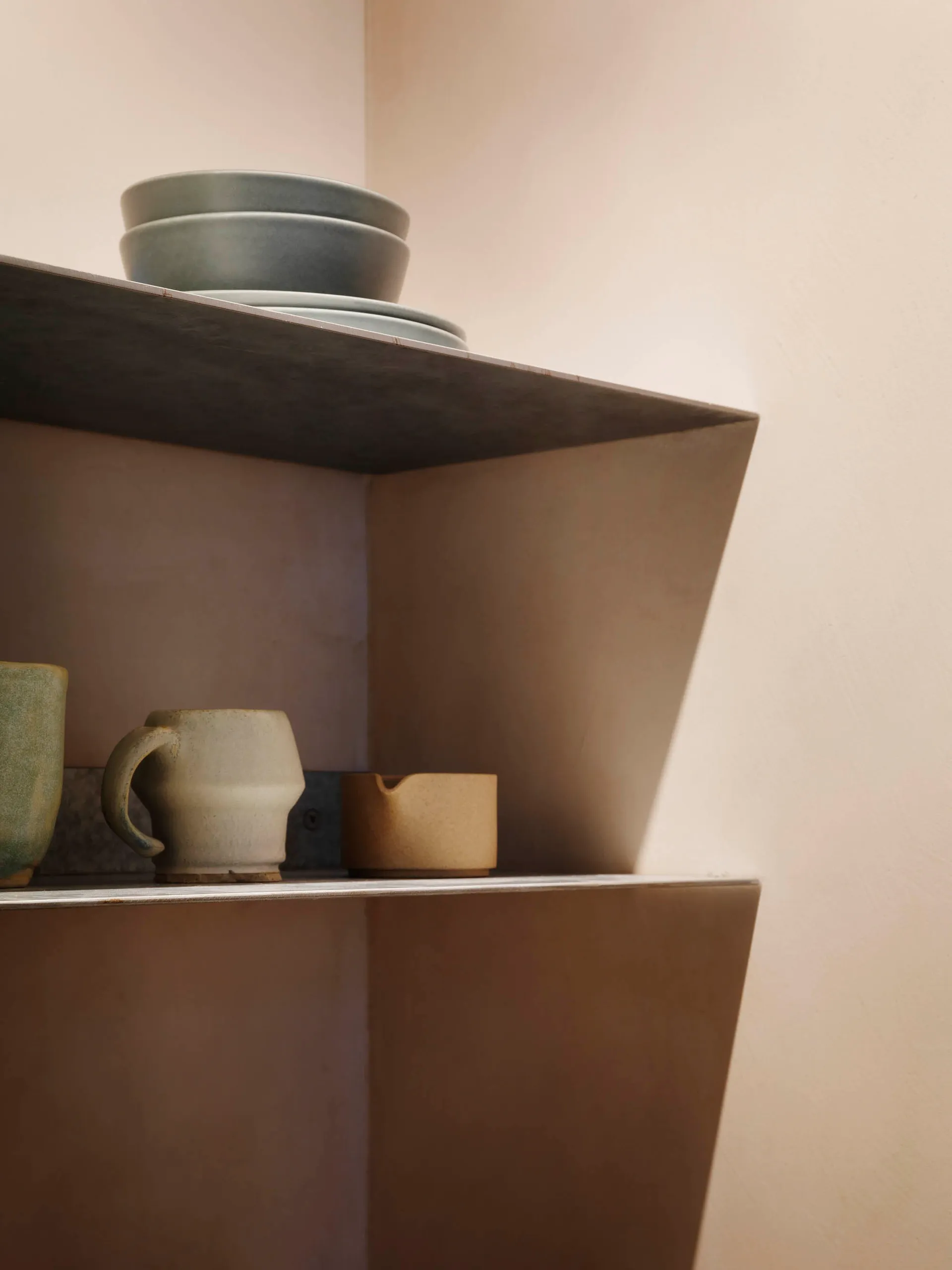 Concrete shelf with ceramic mugs and bowls.