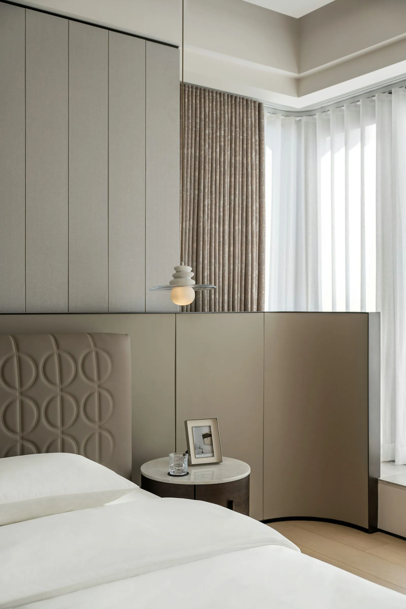 Modern bedroom featuring a taupe headboard and curtain, showcasing minimalist design and cozy atmosphere.