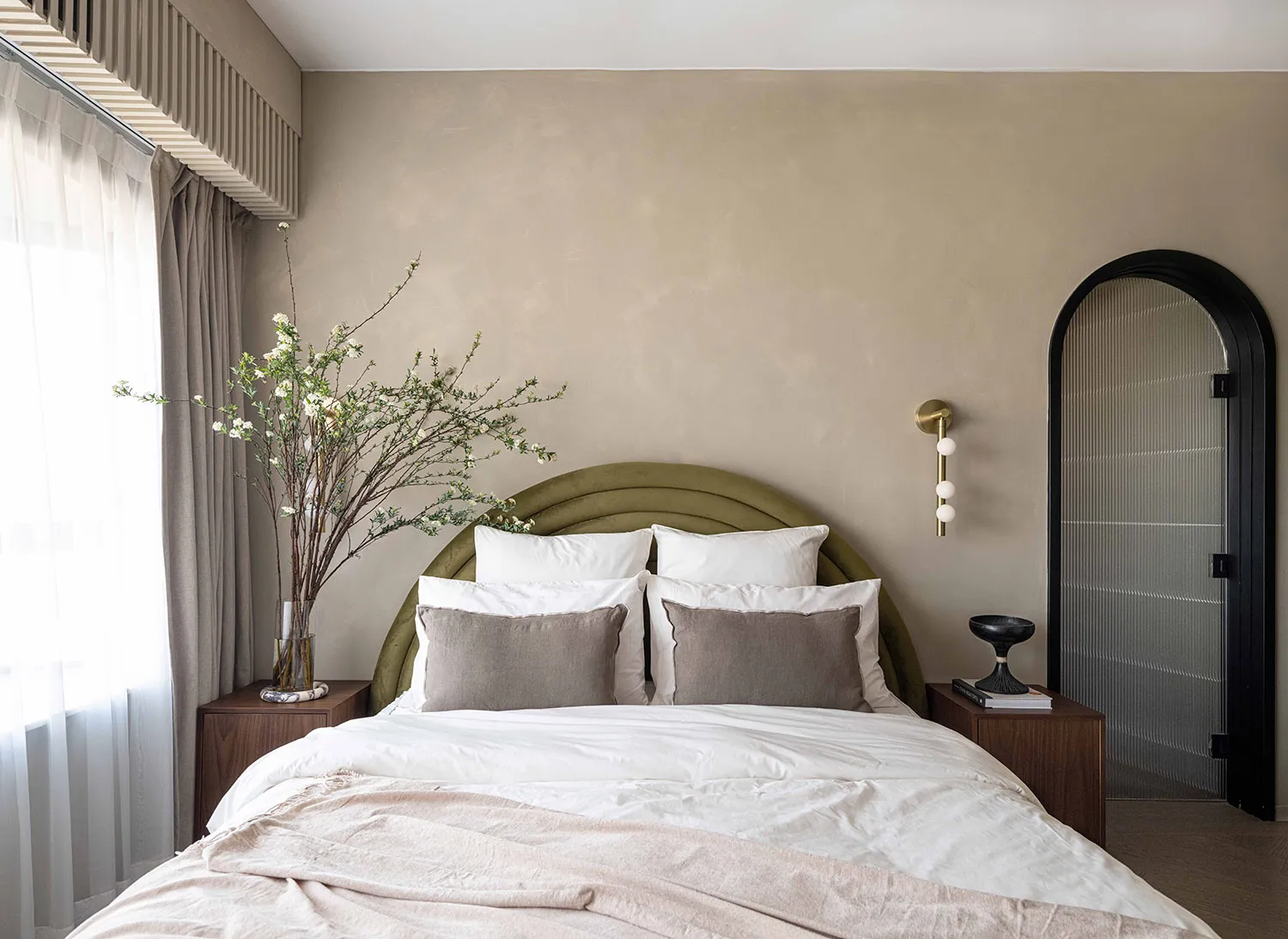 A modern contemporary bedroom with white bedding, white and olive green pillows, and a textured olive green headboard.