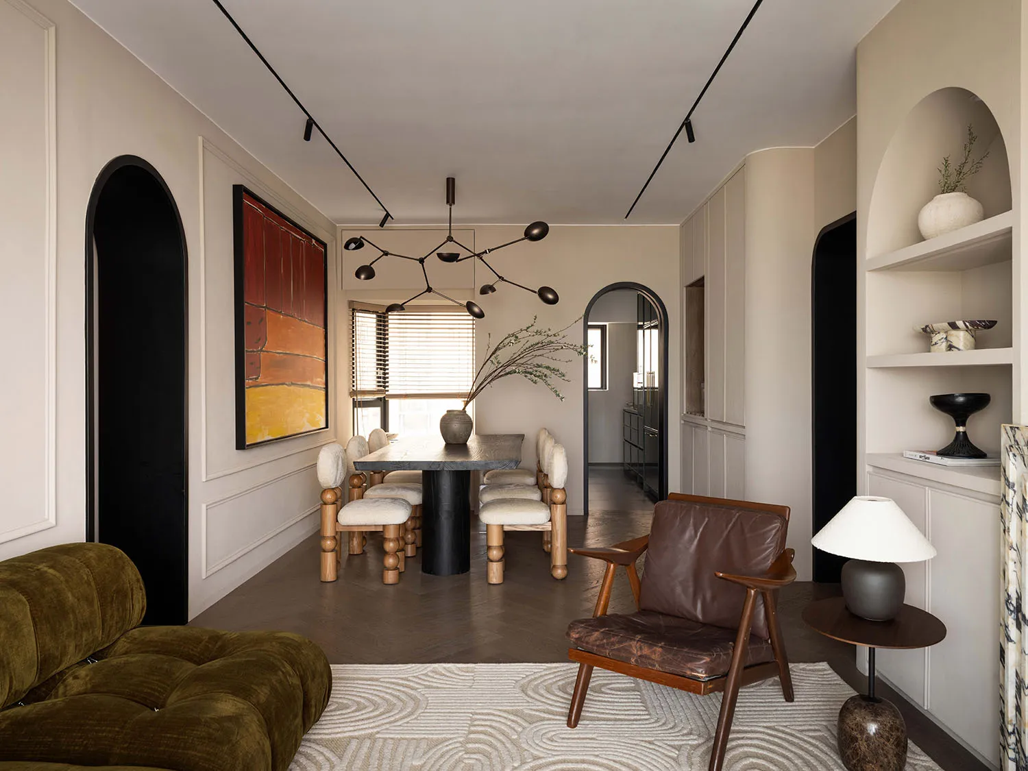 A minimalist dining room with wooden furniture, featuring a black circuit-like pendant light, beige walls, and a patterned ru