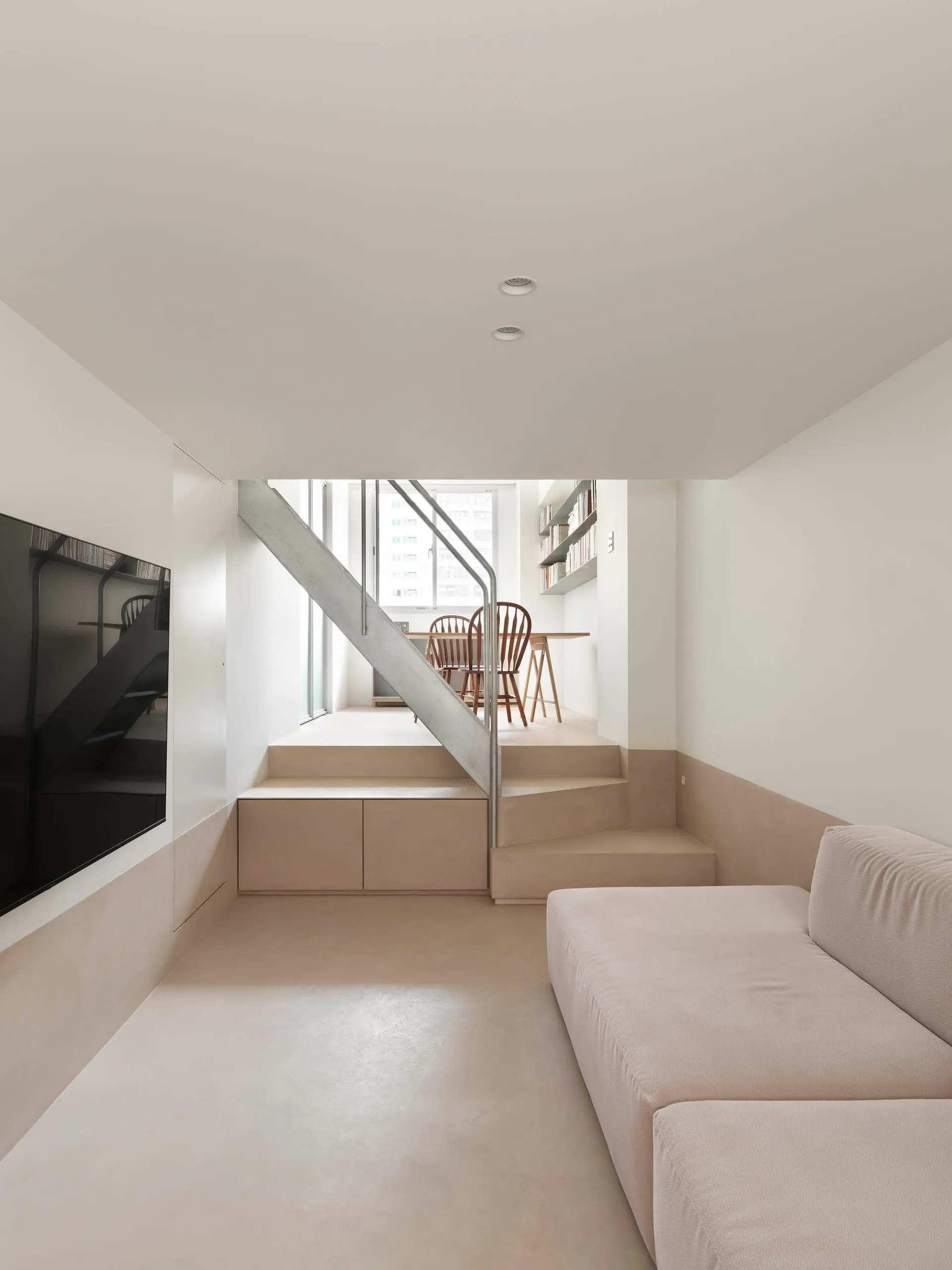 A modern minimalist residential interior with a concrete floor and wooden furniture.