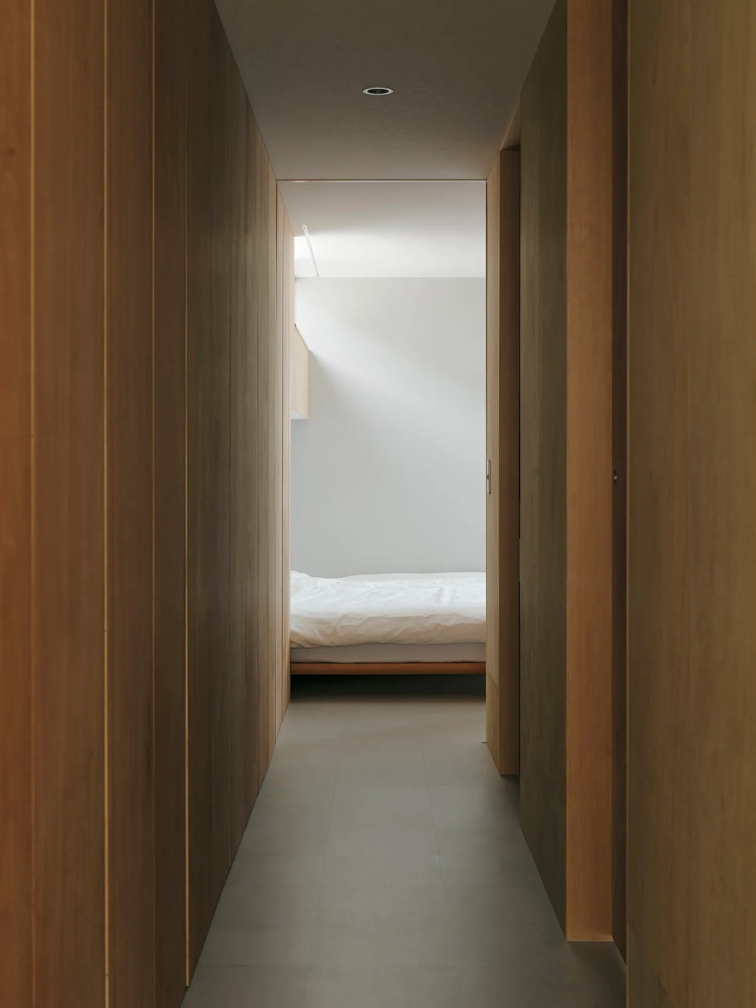 A modern bedroom with wooden walls and a white bed.