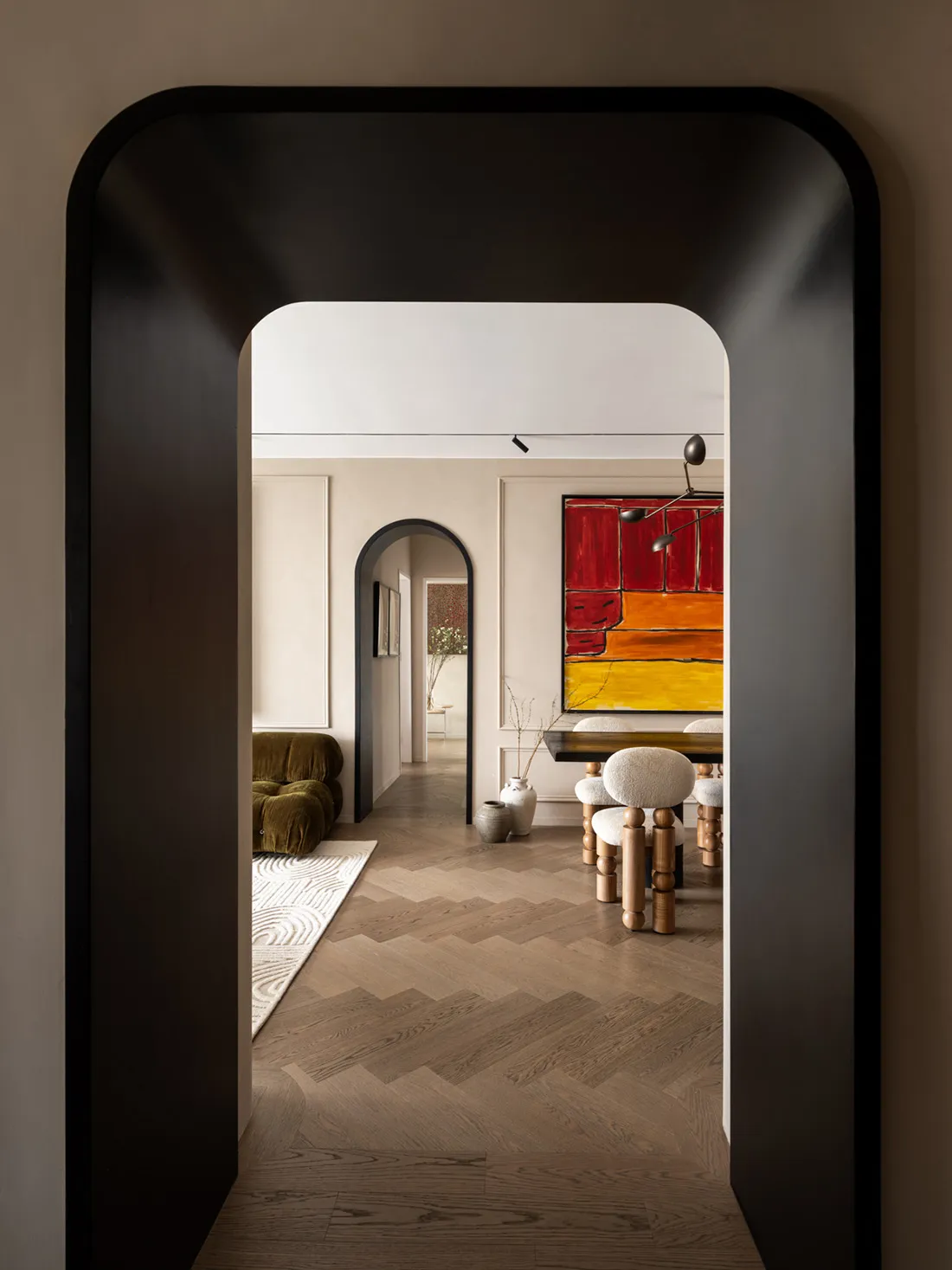 Modern dining room featuring wooden flooring, white walls, and a large colorful abstract painting.