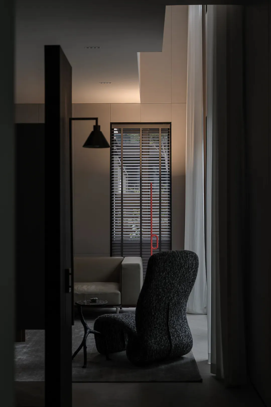 A modern living room featuring a comfortable upholstered chair, minimalist decor, and sleek furniture.