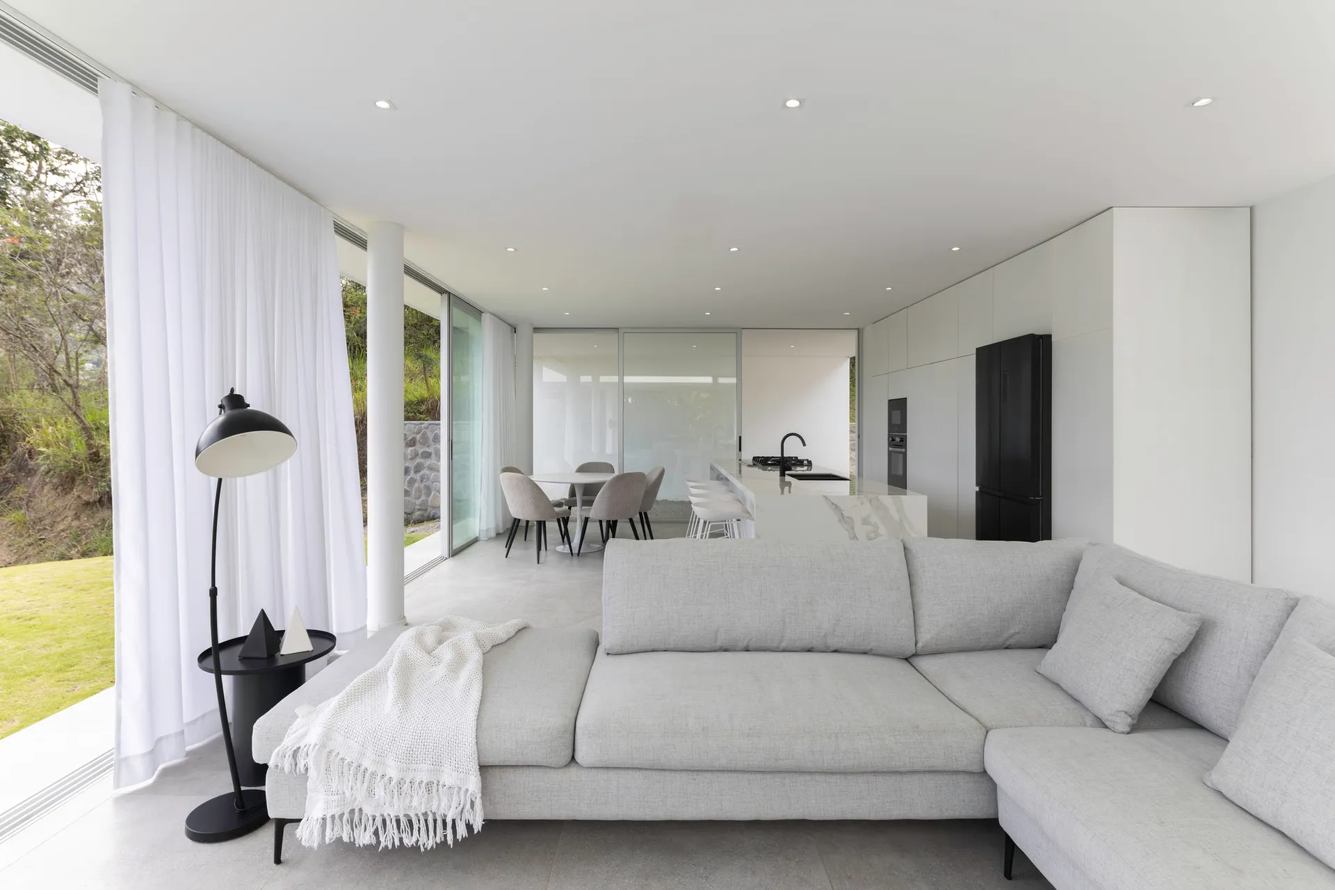 Contemporary living room featuring a large concrete sofa and floor-to-ceiling windows.