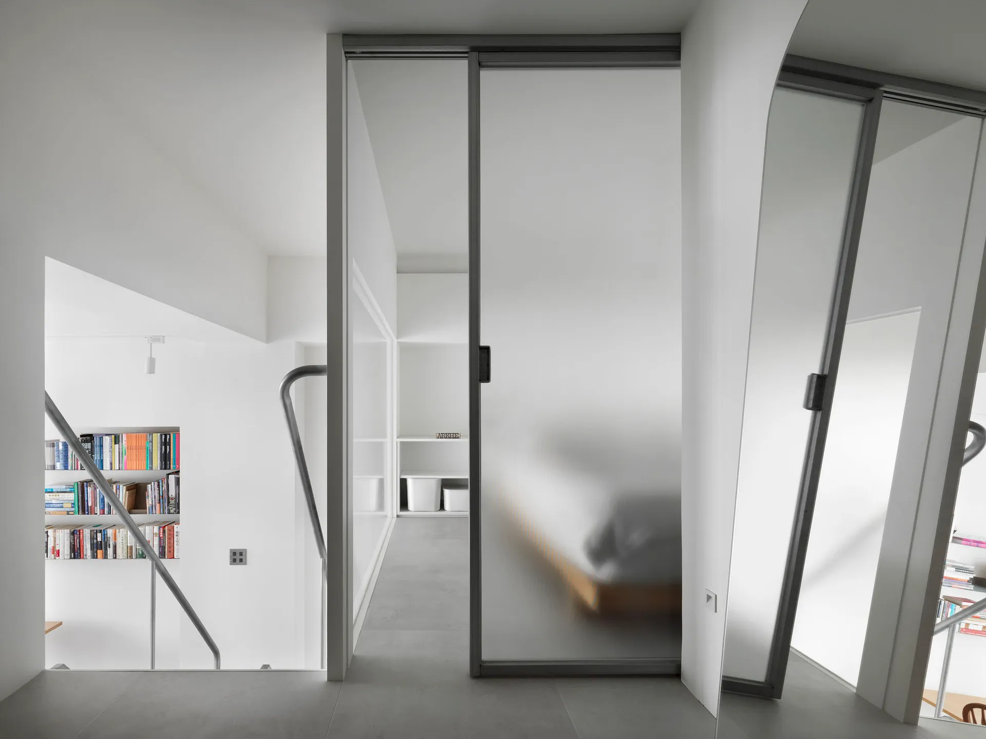 Modern minimalist bedroom with frosted glass doors and white interior design.