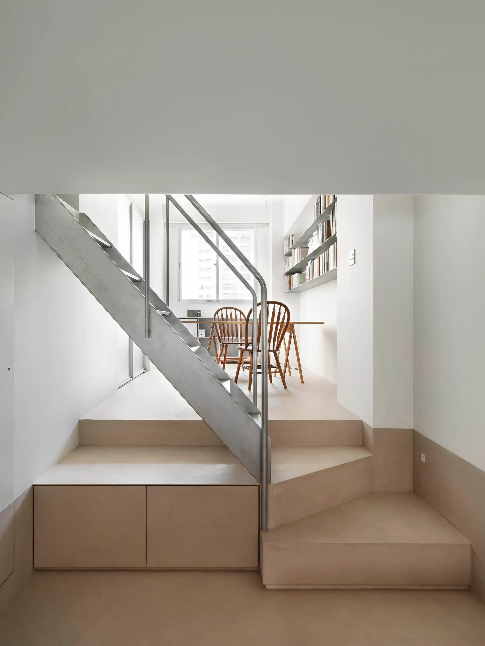 Minimalist concrete staircase with metal railings and integrated seating in a living space.