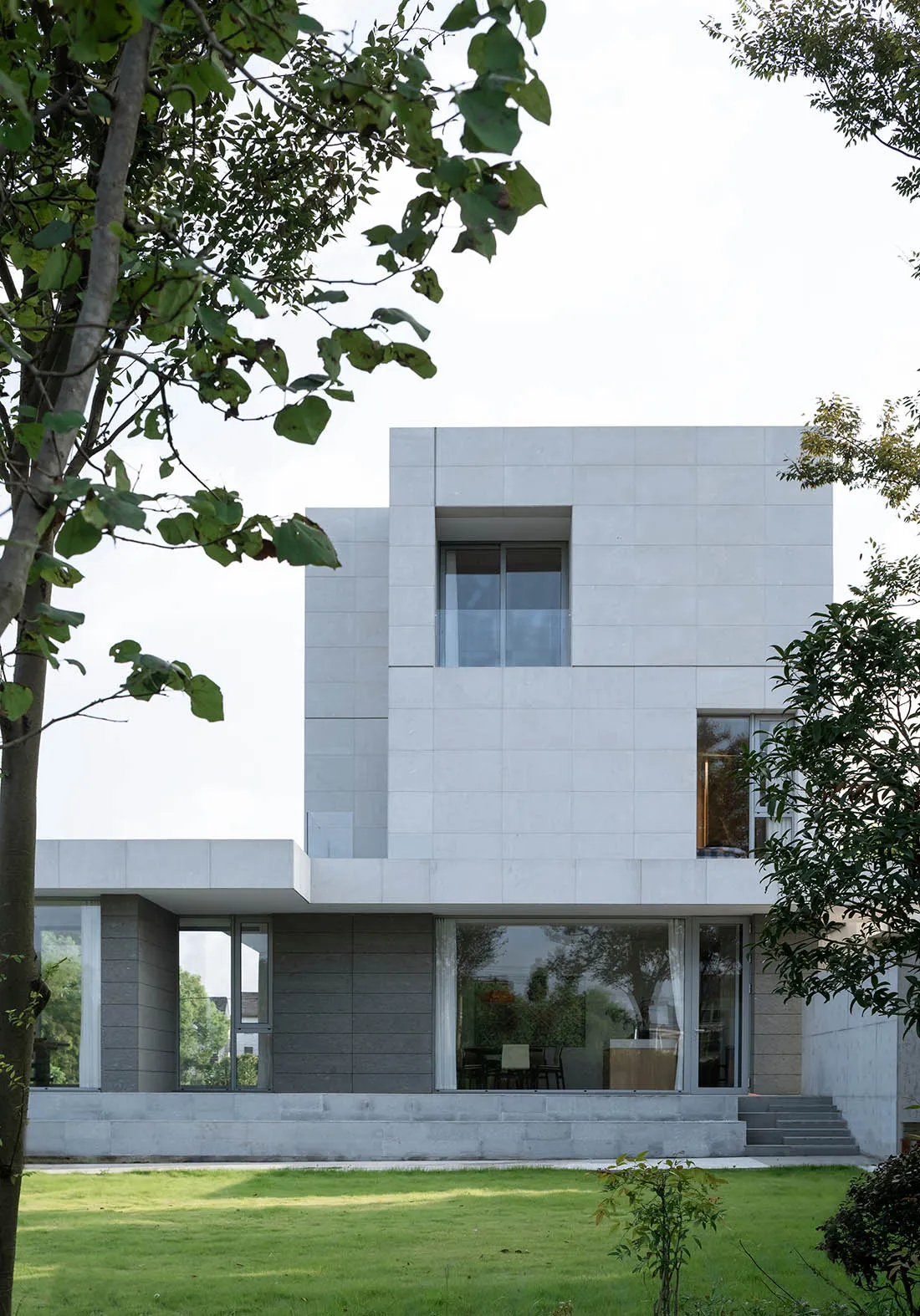 Modern residential building with white concrete exterior and large windows.